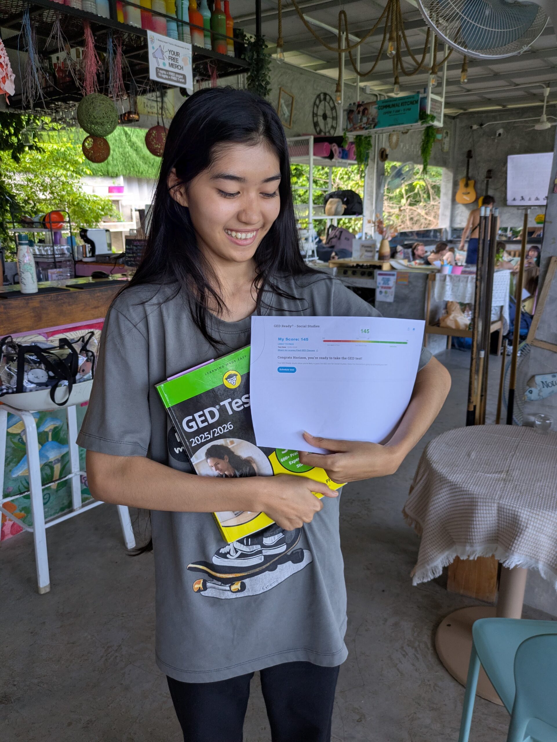 Student reviewing GED preparation materials and practice test results at Wonderland Jungle Hostel, Koh Tao.