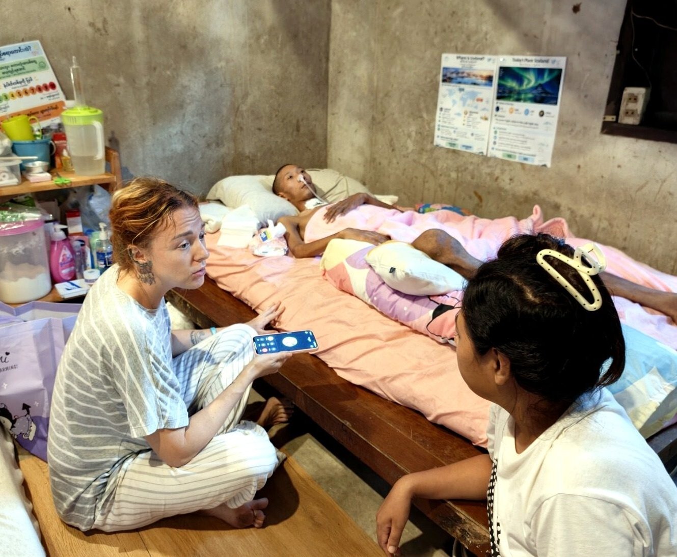 Kin Nage 1 A Horizon Asia team member and a family member talk beside Kin Nage, who lies in bed at home on Koh Tao.